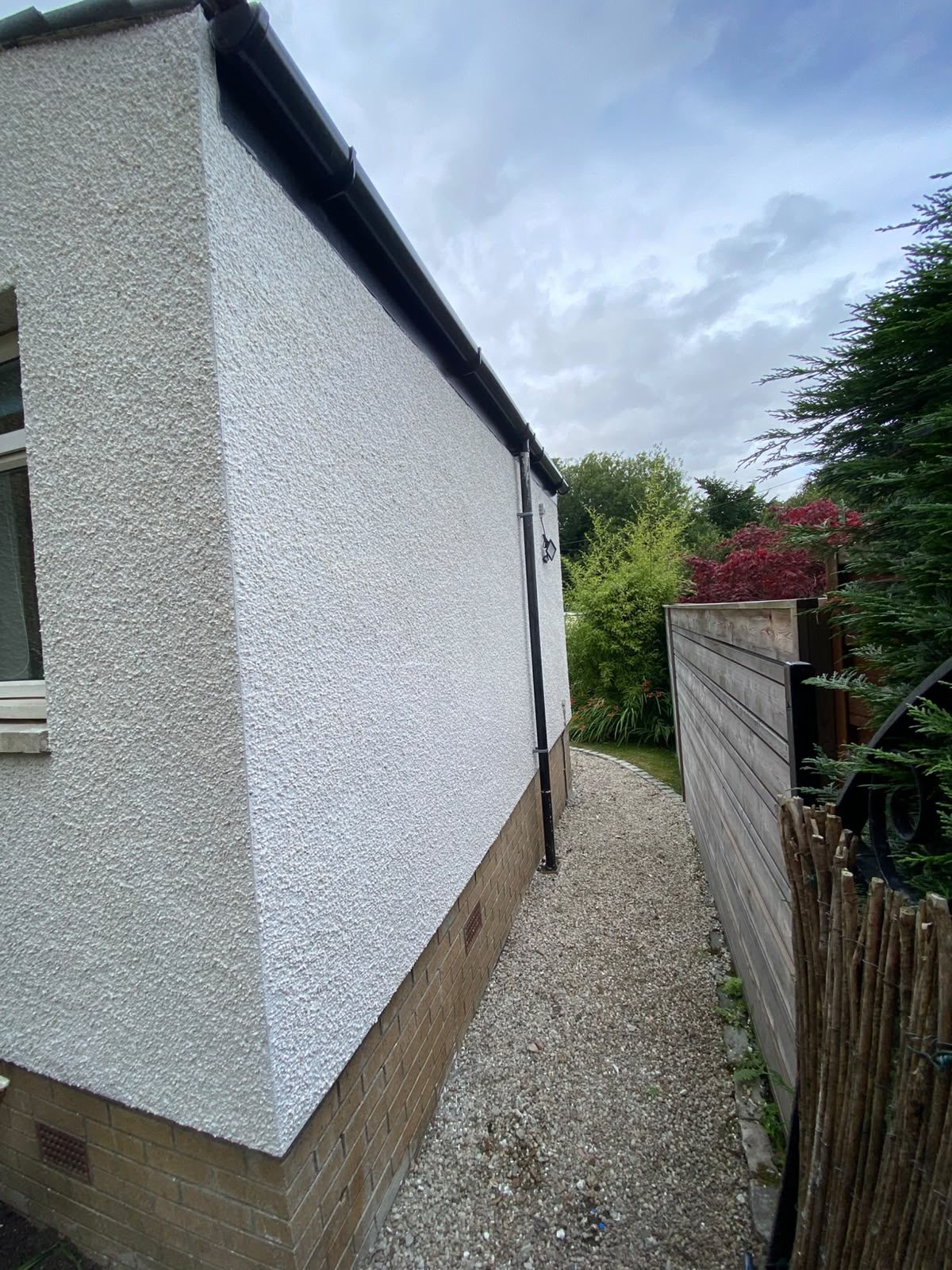 White rendered extension gable with black rainwater goods